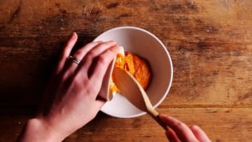 4 tablespoon of thai red paste being spooned into a small mixing bowl