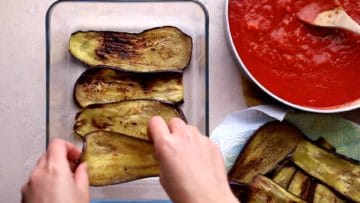 adding first layer of aubergines to base of the baking dish