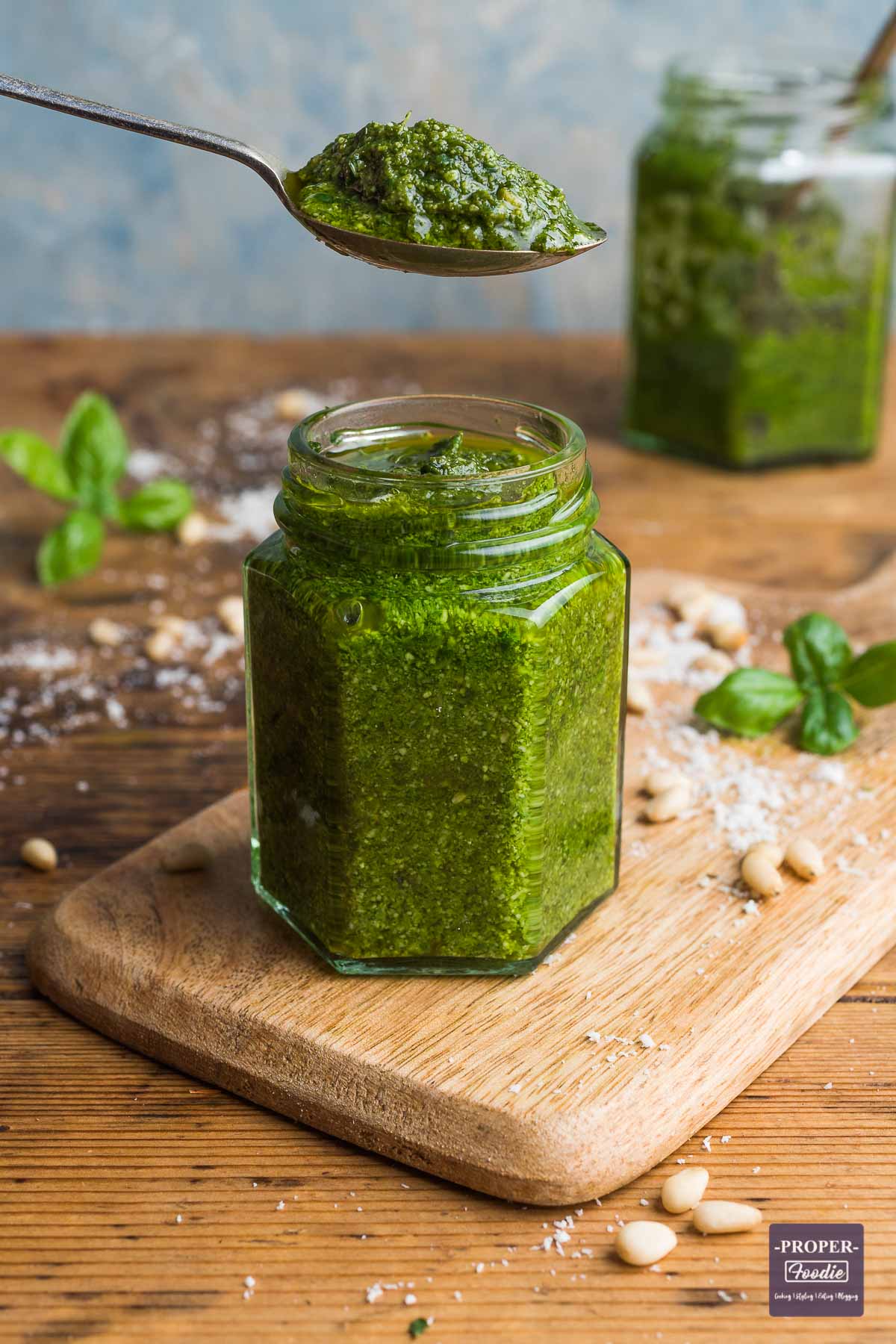 Homemade basil pesto in an open jar with a teaspoon of pesto held above the jar.