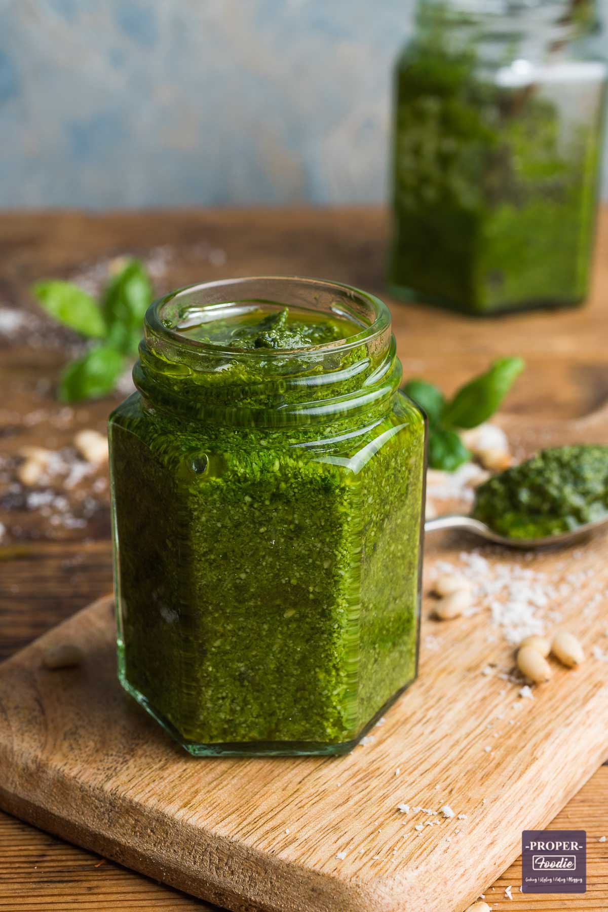 A small jar with the lid off filled with homemade basil pesto.