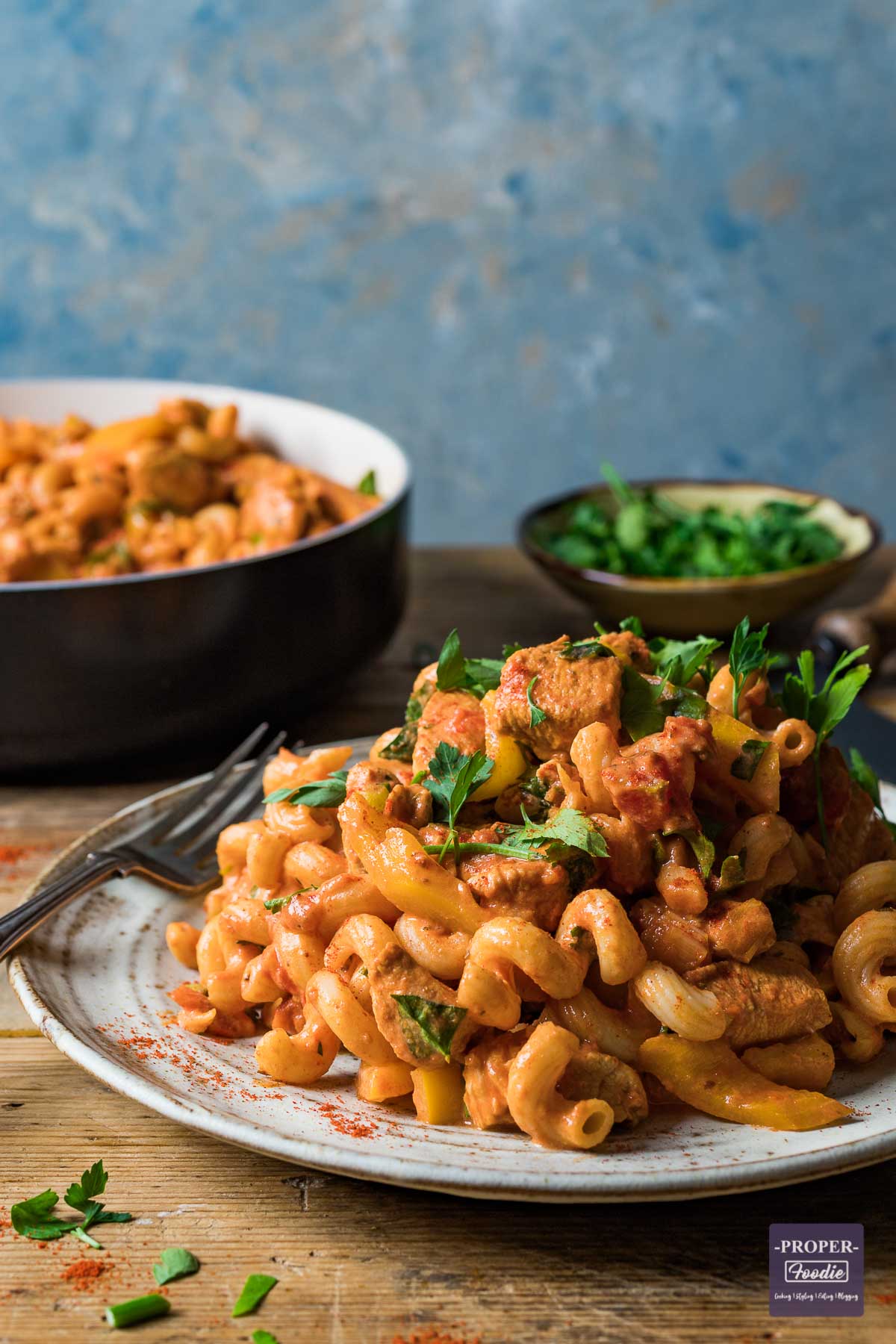 Creamy cajun chicken pasta recipe served on a plate with a pan of extra pasta in the background.