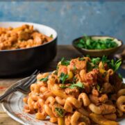 Creamy cajun chicken pasta recipe served on a plate with a pan of extra pasta in the background.