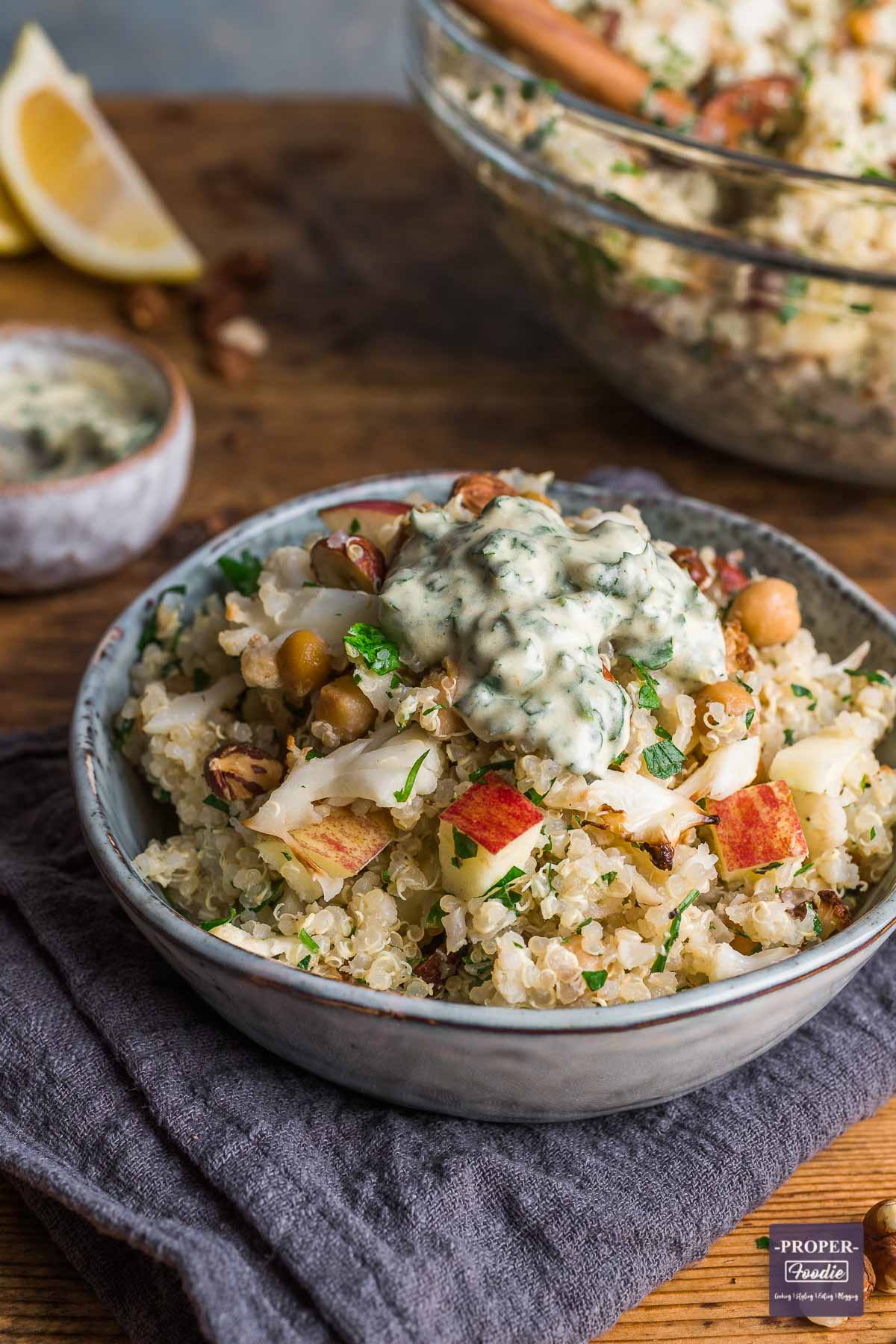 Quinoa and roasted cauliflower salad with lemon & herb dressing, served in a small bowl sat on a blue napkin.