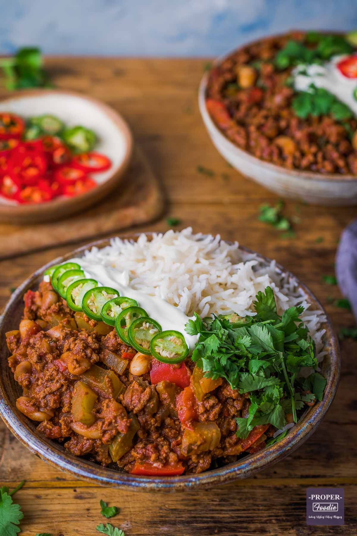 chilli con carne in half a bowl with rice in the other half and a second bowl of chilli in the background.