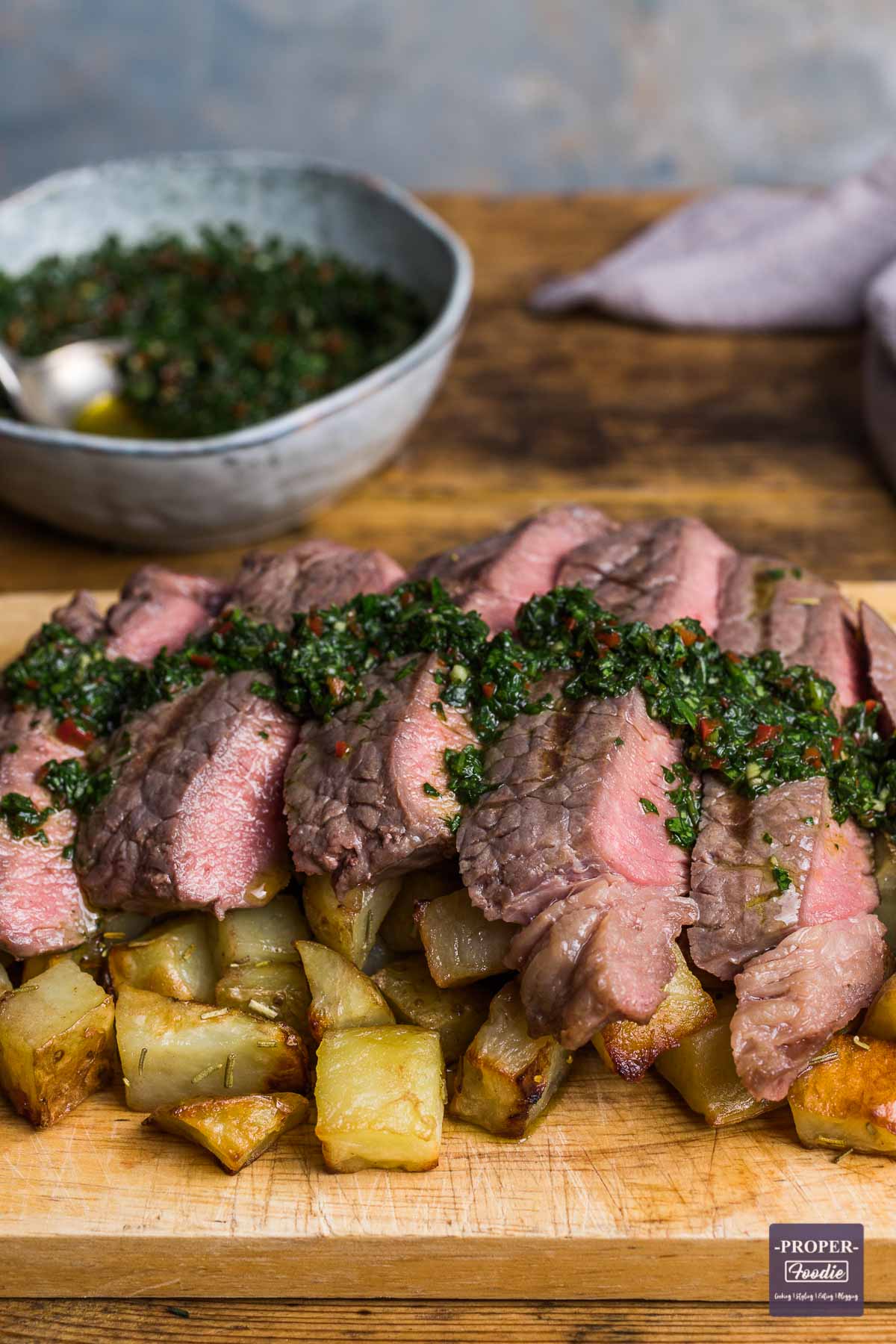 Slices of rump steak cooked medium rare and served over cubed potatoes with a chimichurri dressing drizzled over the top.