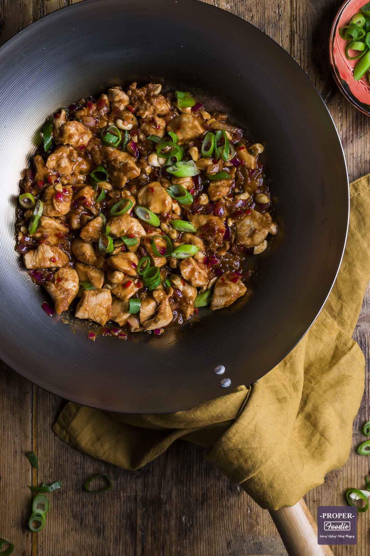 Dragon chicken recipe in a pan topped with sliced spring onions.