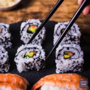 california rolls served on a black slate platter with a pair of chopsticks