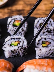 california rolls served on a black slate platter with a pair of chopsticks