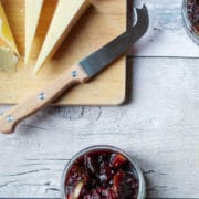 Homemade Fig and apple chutney in a small dish next to wedges of cheese and crackers on a board