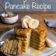 Stack of banana pancakes topped with sliced bananas, and with a wedge skewered and cut out from one side of the pancake stack and put to the side.