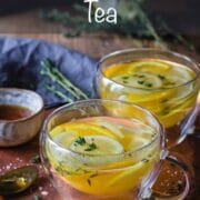 Steamy cup of lemon tea in a glass teacup sat on a bronze mottled tray.