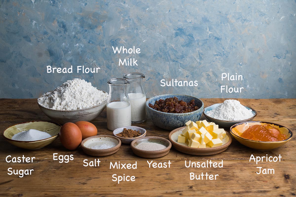 A display of the ingredients needed to make hot cross buns with text overlay stating each ingredients.