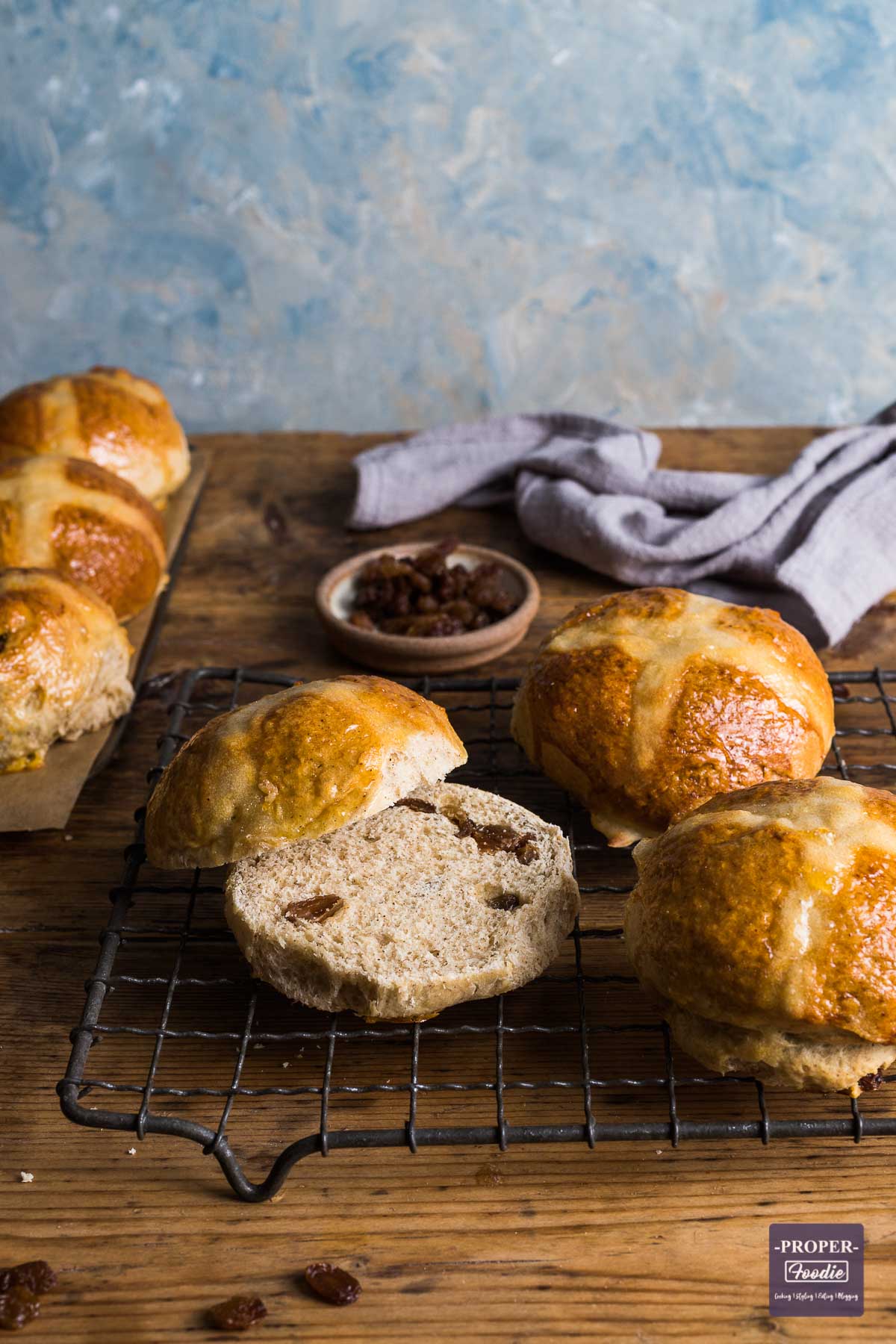 Hot cross buns on a cooling rack with one sliced in half