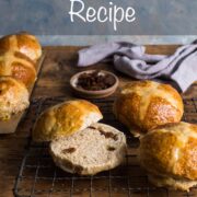 hot cross buns on a cooling rack with one sliced in half