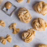 Homemade strips of pasta wrapped into nests with text overlay: How To Make Pasta.