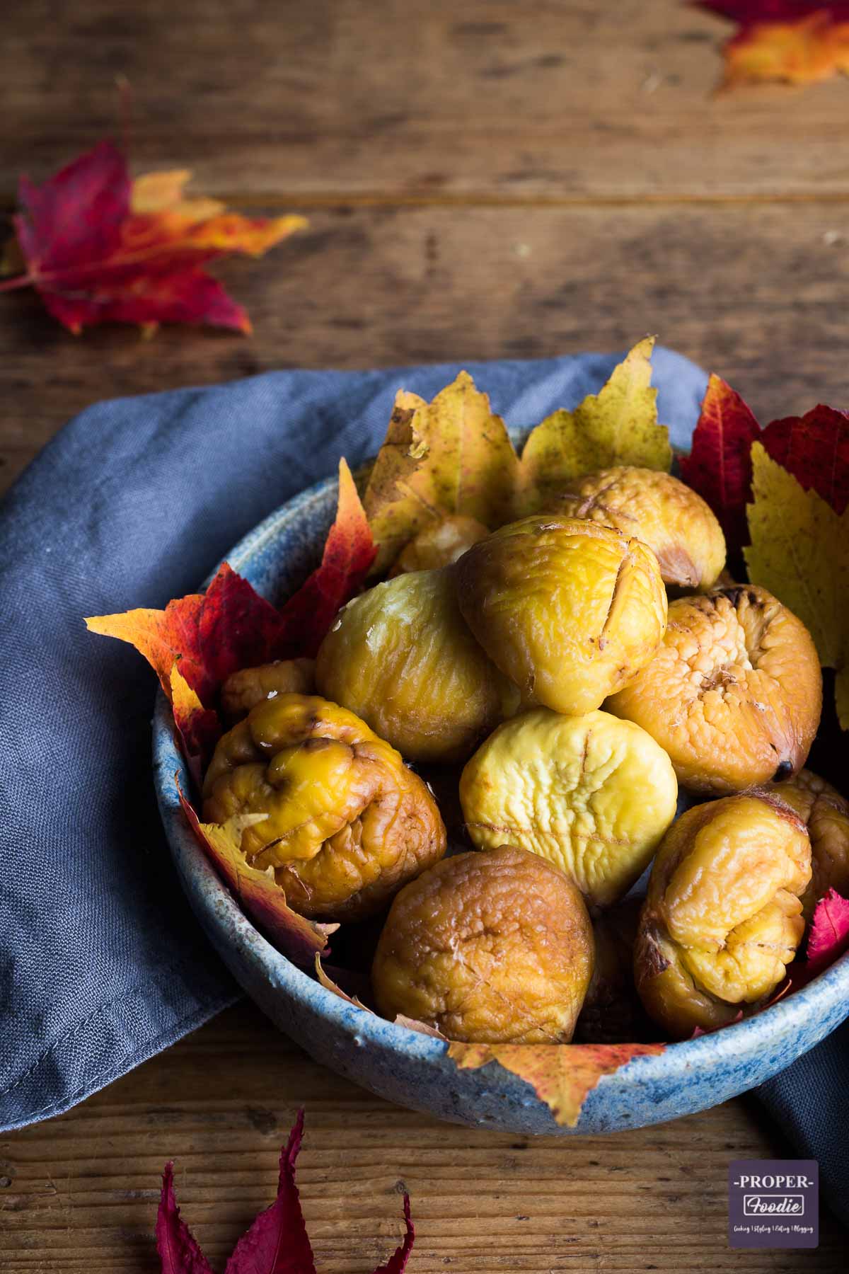 Bowl of roasted and peeled chestnuts with autumnal leaves lining the bowl.