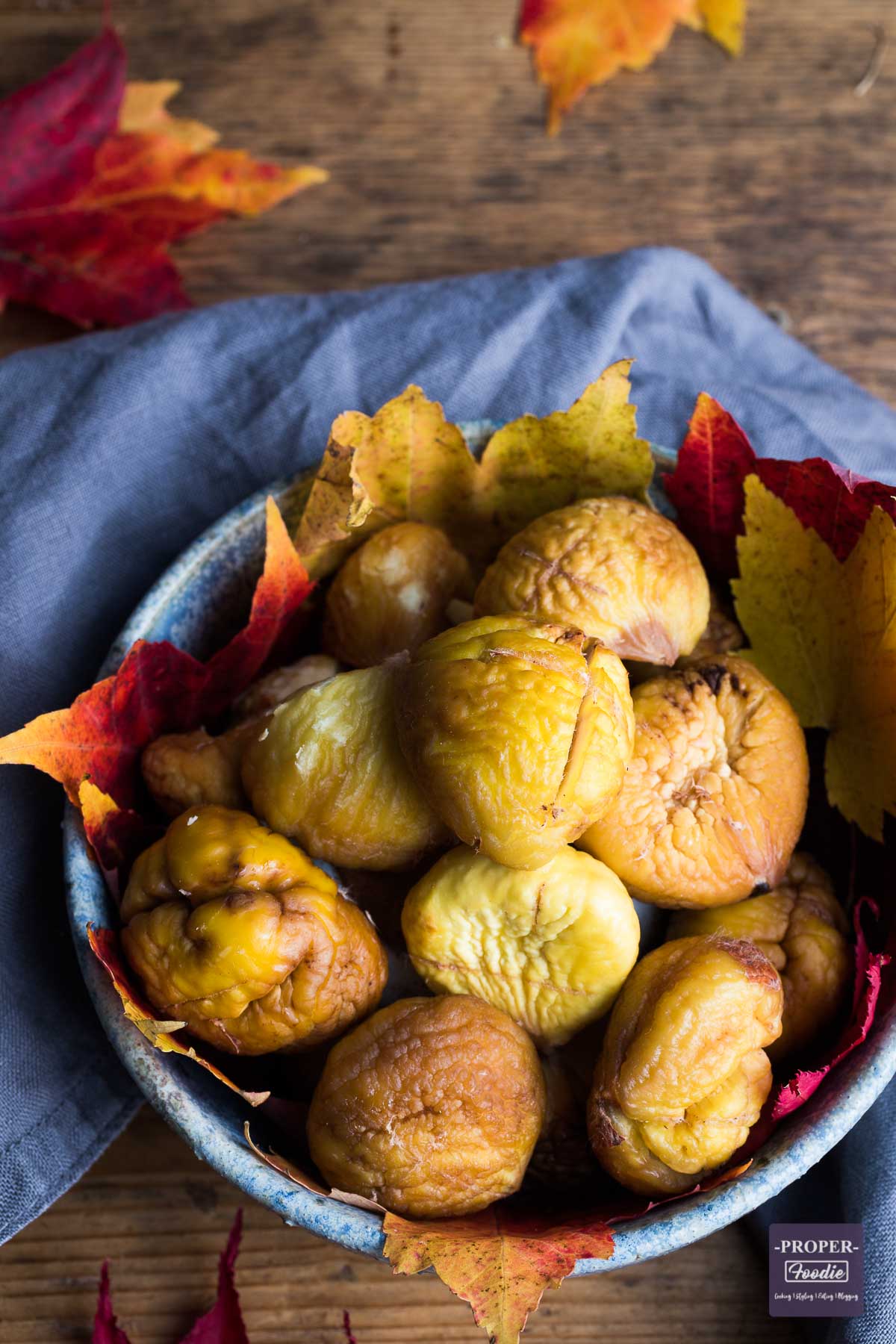 Bowl of roasted and peeled chestnuts with autumnal leaves lining the bowl.