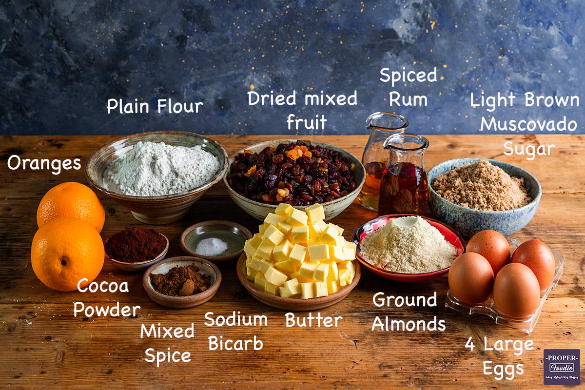 A display of all the ingredients needed to make a Christmas cake with text overlay labelling each ingredient.