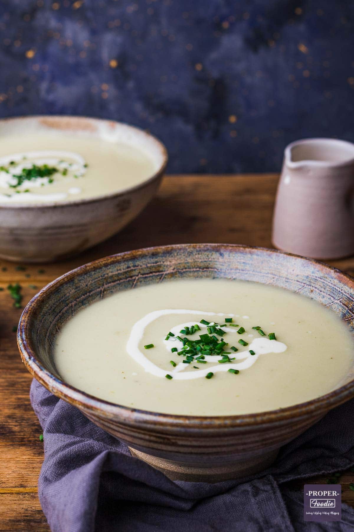 A bowl of homemade leek and potato soup with a second bowl of soup in the background.