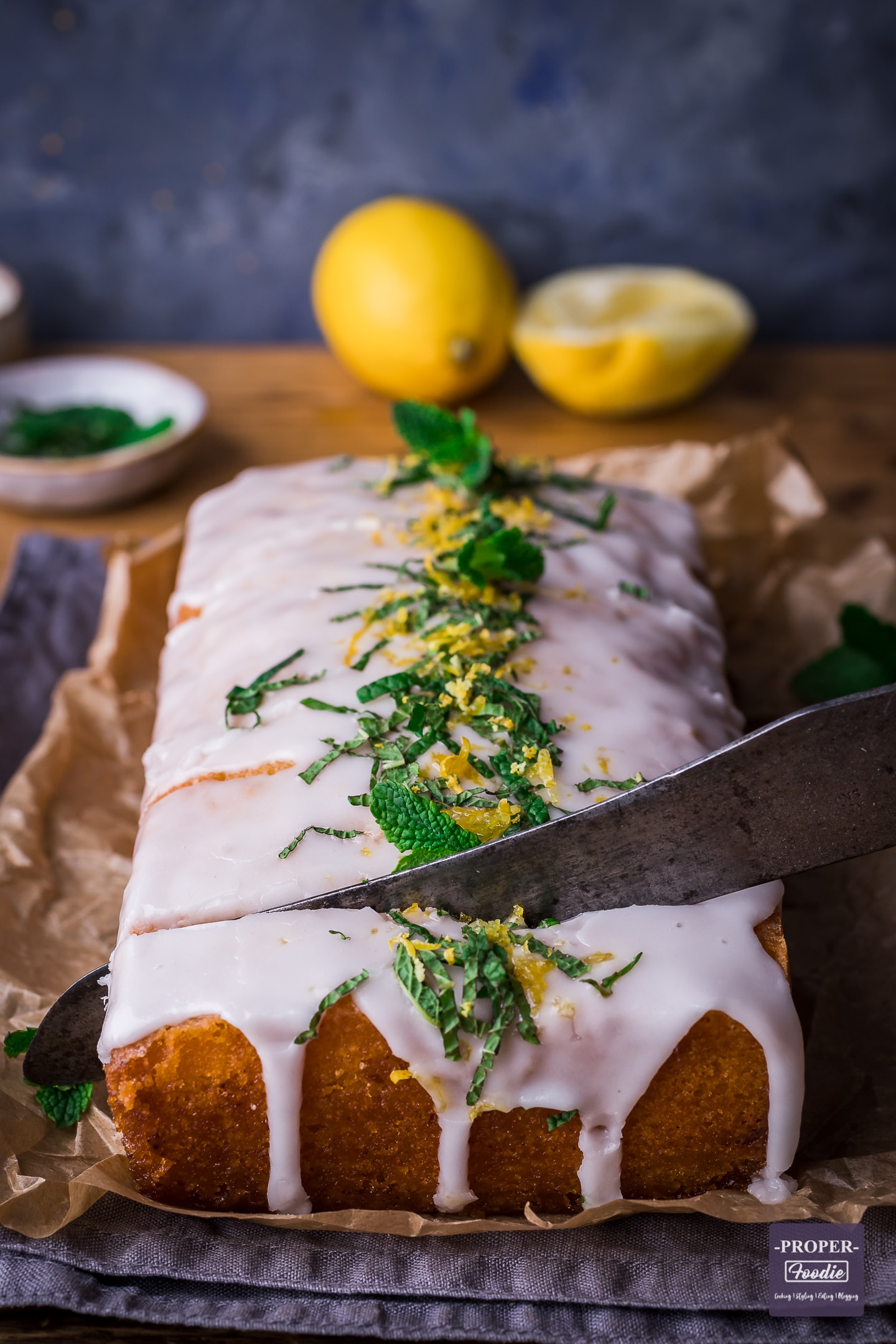 Lemon drizzle cake with lemon icing being sliced into with a knife