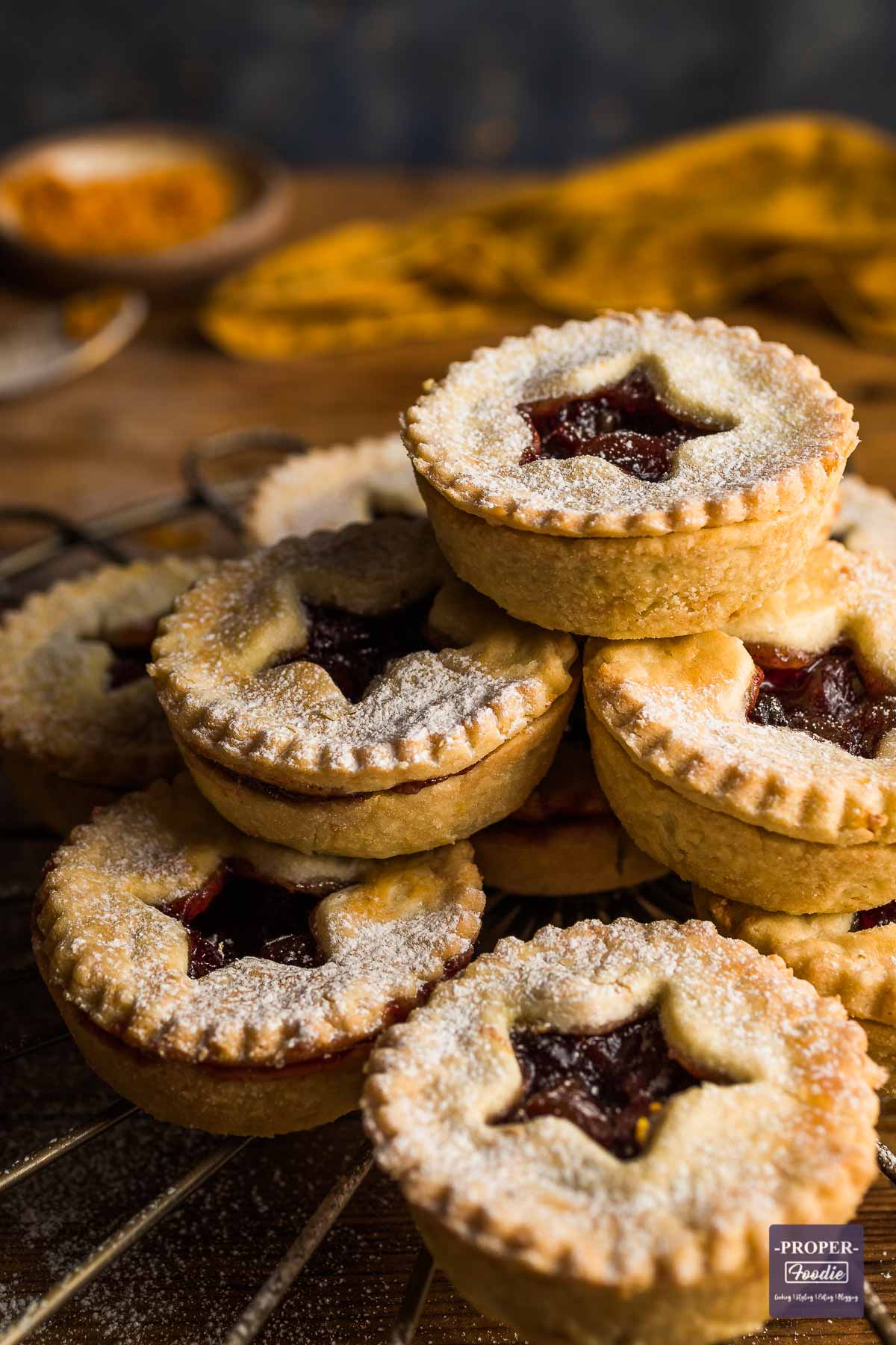 A stack of homemade mince pies with star shapes cut out of the pastry lids.