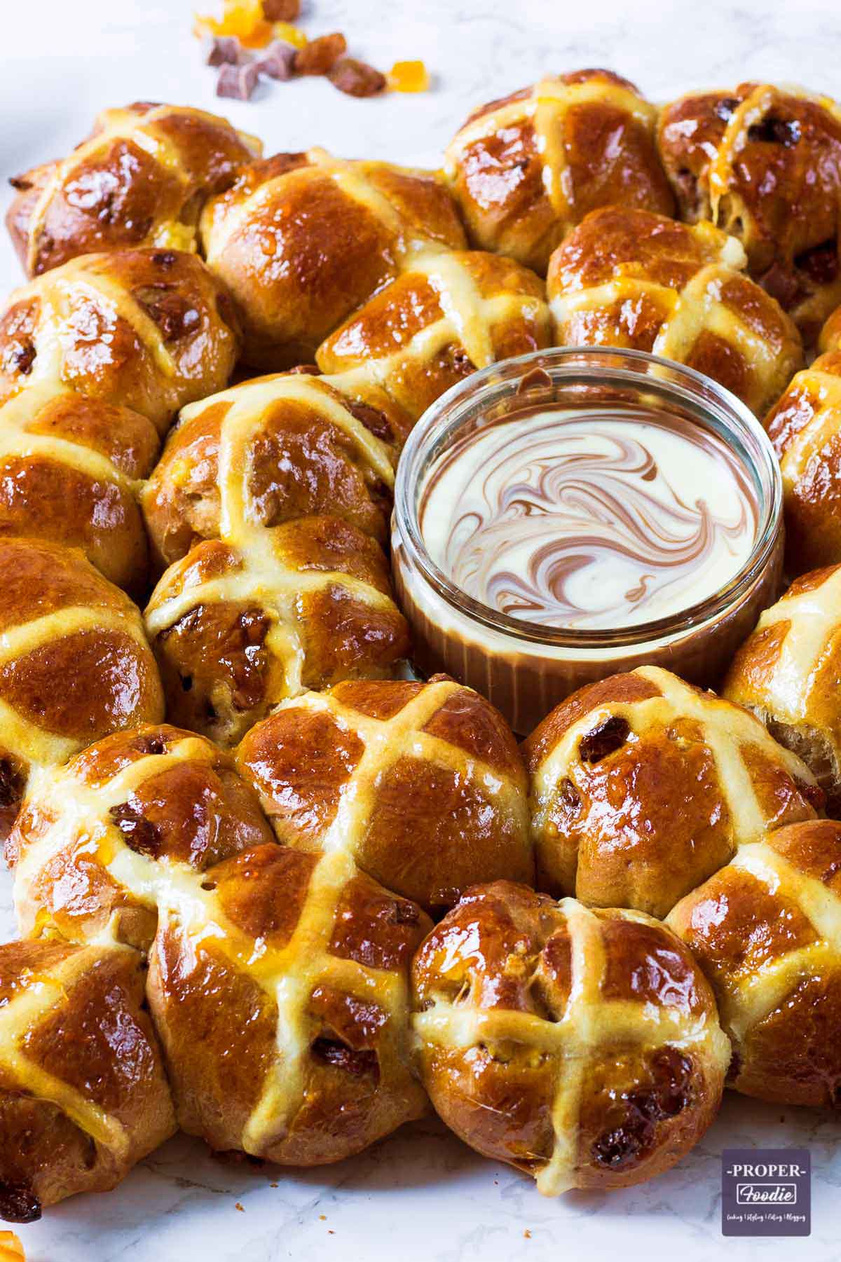 mini hot cross buns bakes in a ring shape with melted chocolate dip.