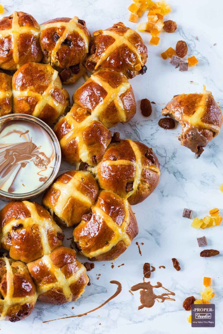 Small hot cross buns arranged in a tear and share style ring with melted chocolate dip at the side.