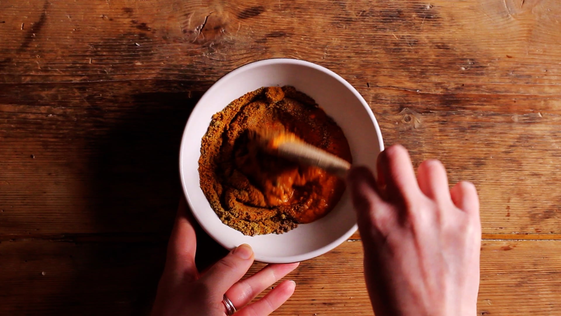 mixing together red paste with coriander, curry powder, cumin and black pepper to make thai yellow paste