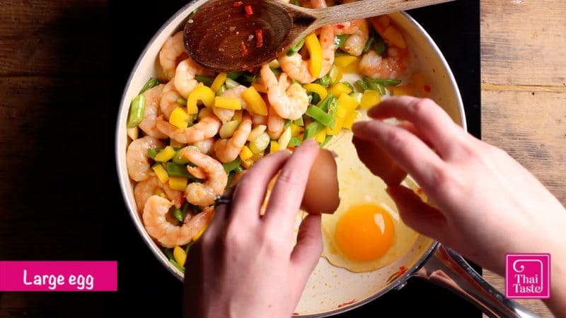 move the pad thai ingredients to one side of the pan, crack in an egg and scramble