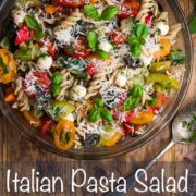 Large bowl filled with cooked fusilli pasta, colourful tomatoes, cucumber, mozzarella pearls and topped with basil leaves and grated pecorino.