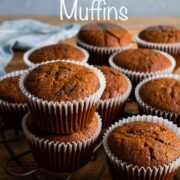 Half of a round cooling rack visible, with pumpkin muffins resting on top in their liners with text overlay: Spiced Pumpkin Muffins.