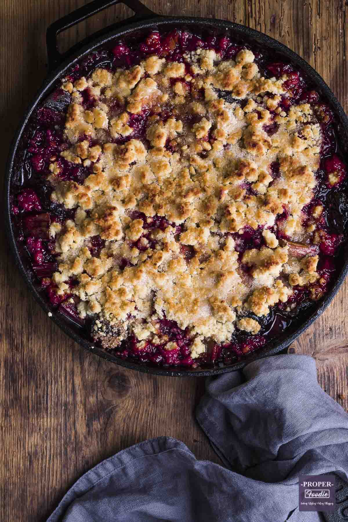 plum and rhubarb crumble cooked in a cast iron pan.