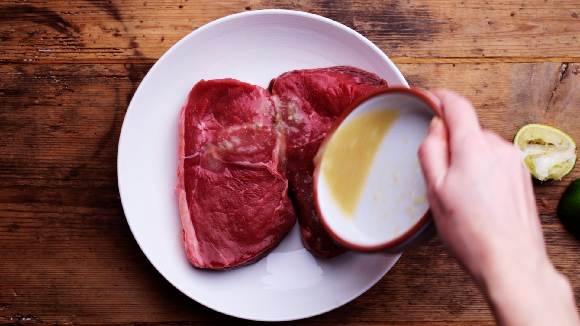 pouring lime marinade over steaks