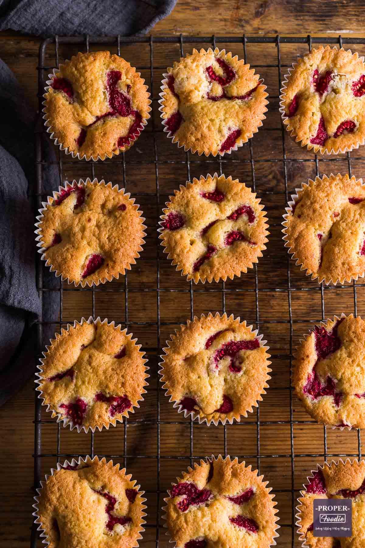 Raspberry and lemon muffins on a wire rack viewed from above with bits of raspberry visible on the top of each muffin.