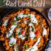 Red lentil dahl in a wide cast iron pan and topped with yogurt and parsley.