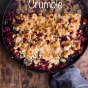 Homemade plum and rhubarb crumble in a cast iron pan with text overlay : Plum and Rhubarb Crumble