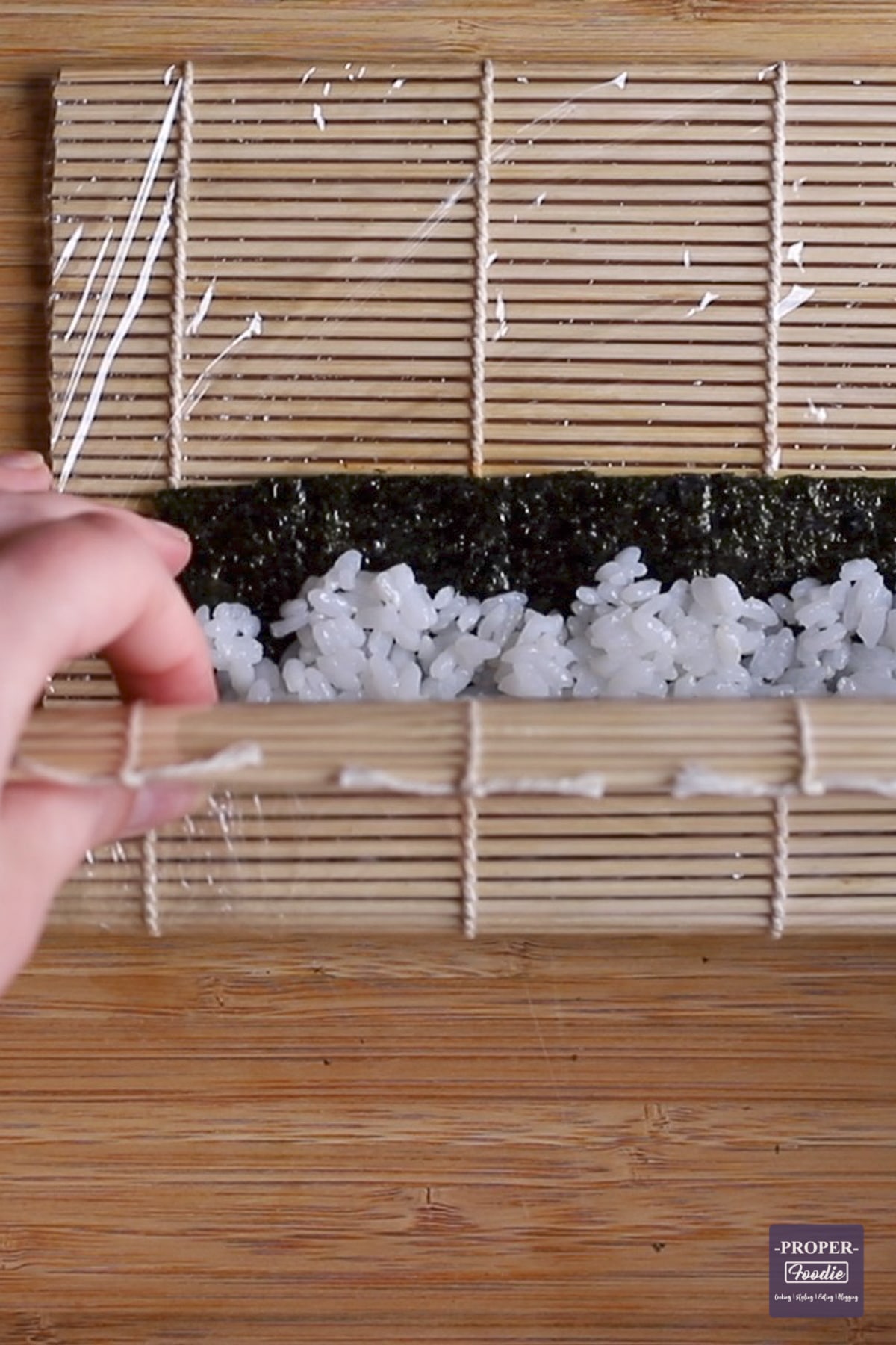 nori and rice being rolled with a bamboo mat