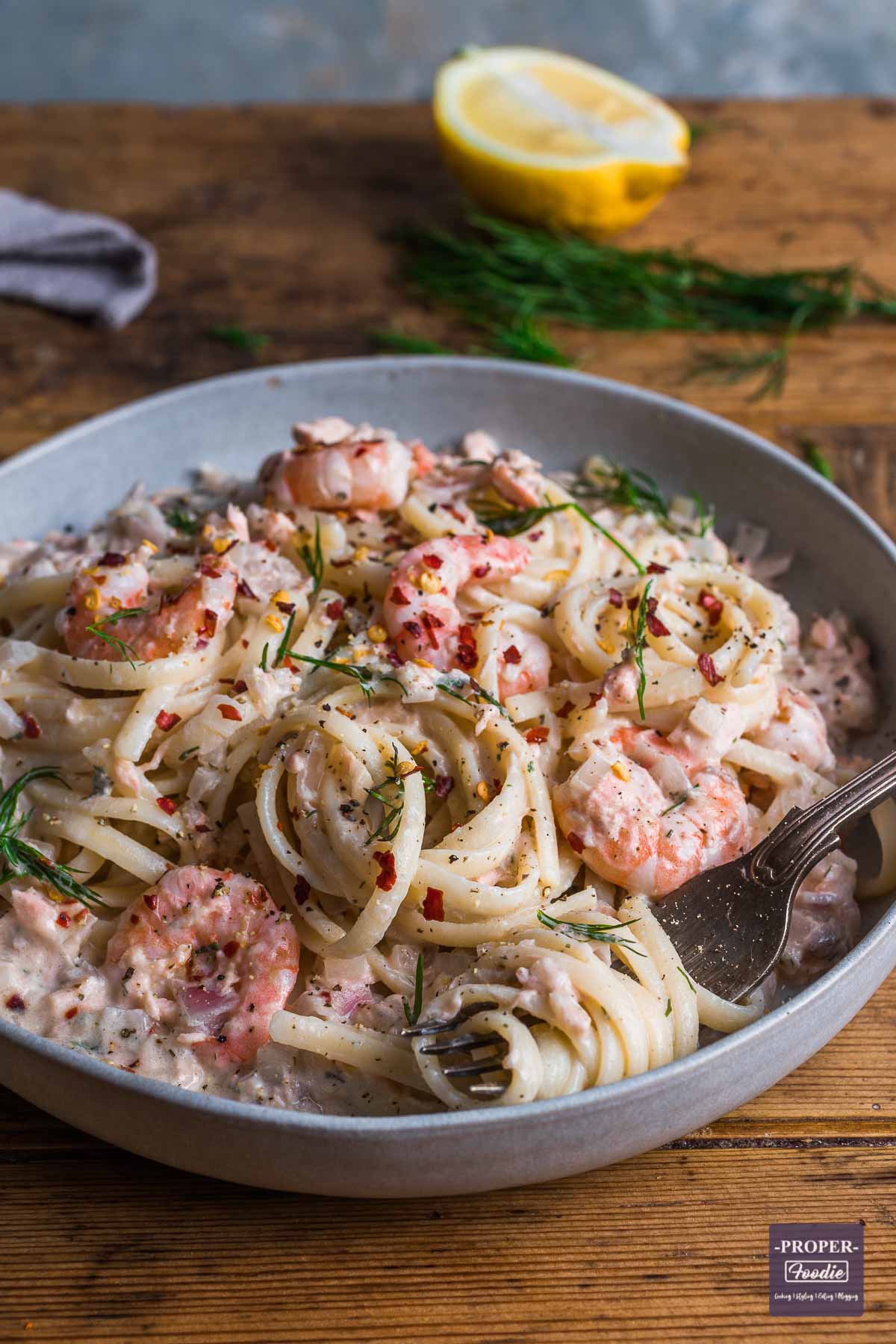 A bowl of linguine in a creamy sauce with salmon and prawns