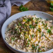 Creamy salmon pasta in a large blue bowl and topped with freshly chopped parsley and lemon zest.