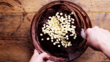 stirring white chocolate chips into brownie mix