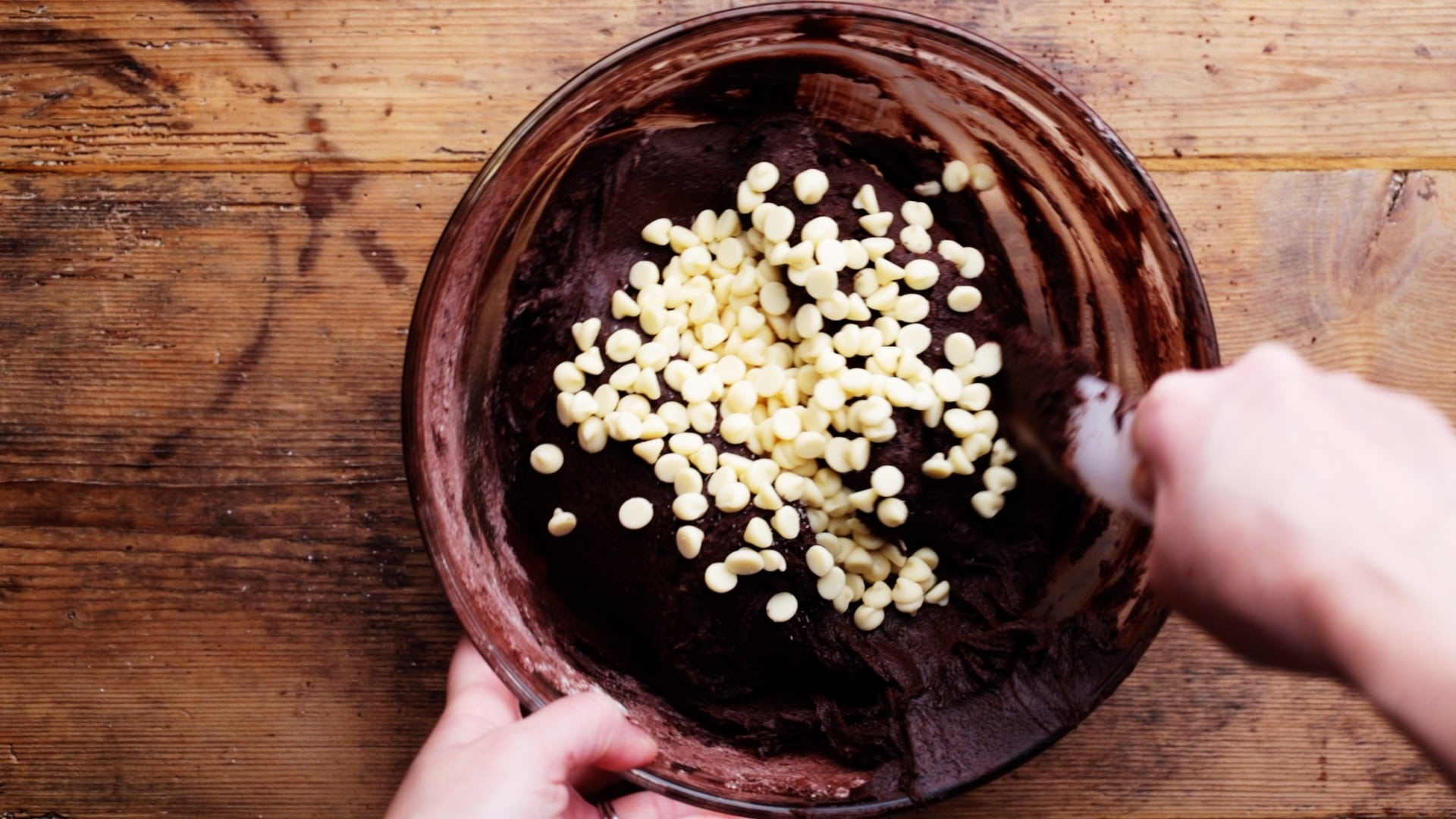 stirring white chocolate chips into brownie mix