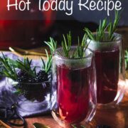 purple hot toddy drink served in two double wall, tall glasses and presented on a bronze tray with sprigs of rosemary