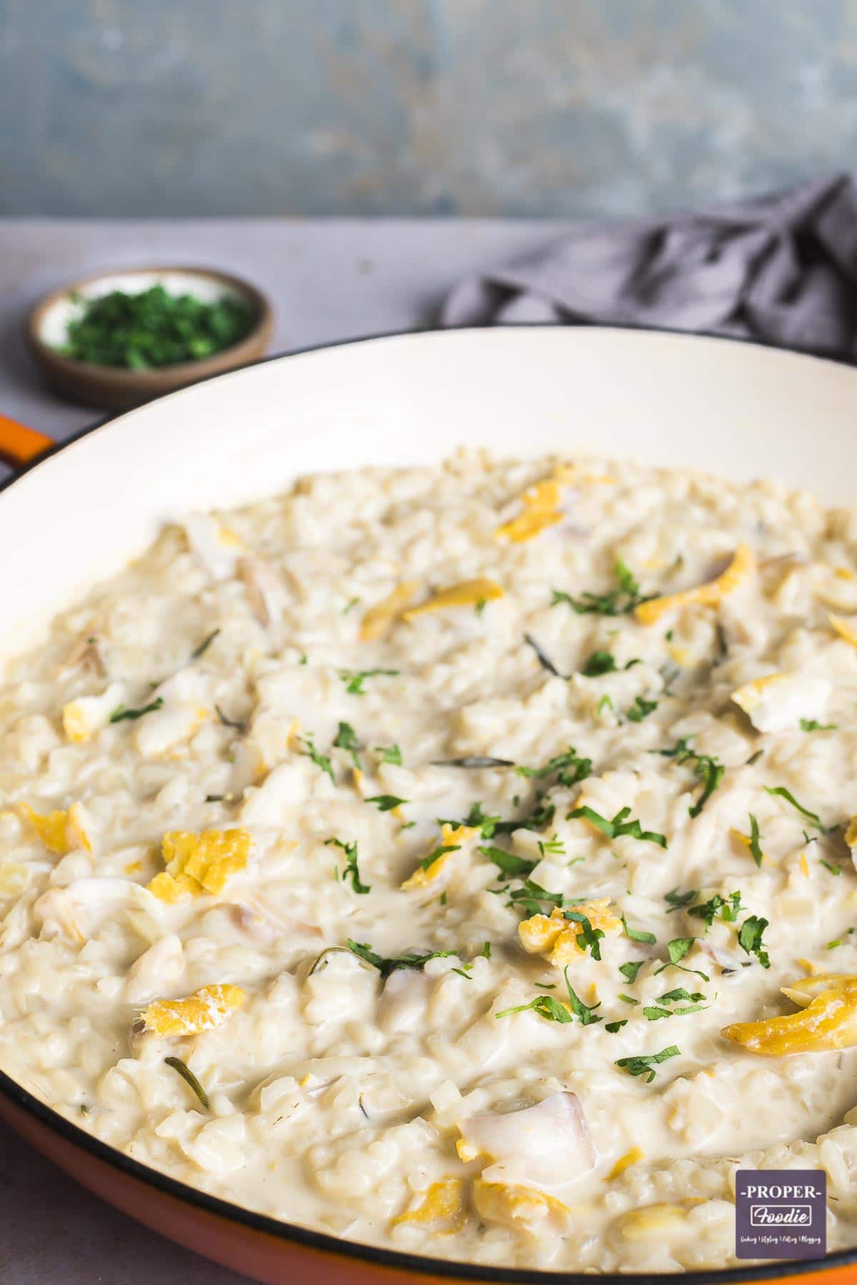 Large shallow casserole dish filled with creamy smoked haddock risotto and topped with parsley.