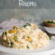 Creamy smoked haddock risotto piled neatly on a small plate, with parmesan being sprinkle on top.