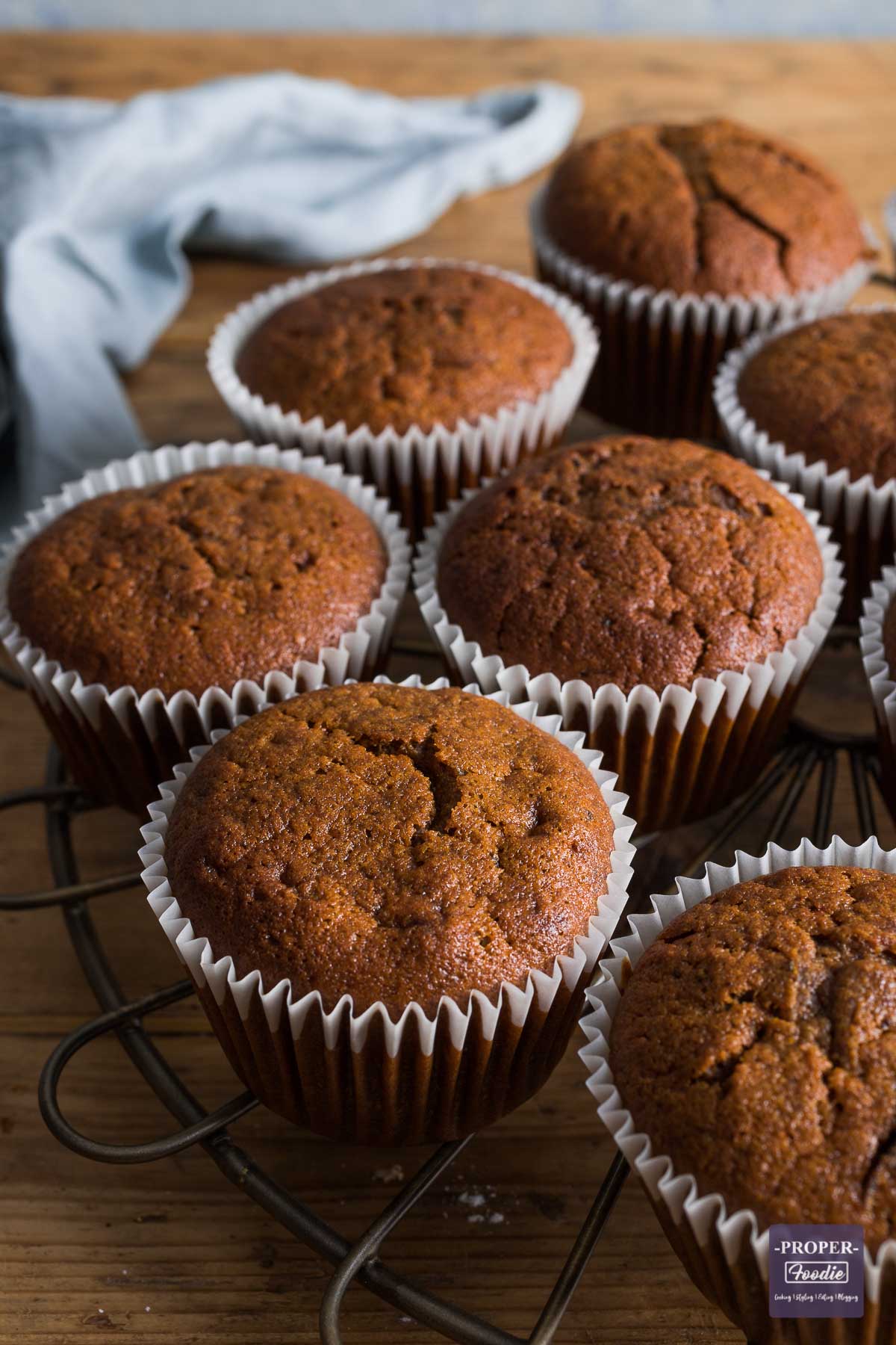 Half of a round cooling rack visible, with pumpkin muffins resting on top in their liners