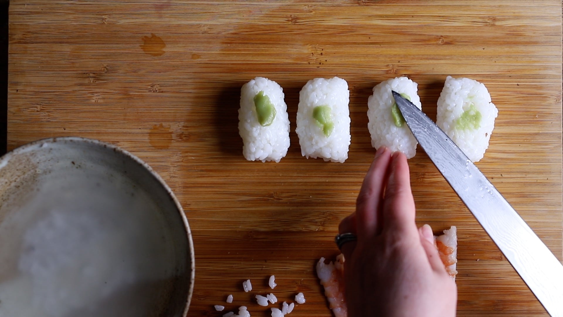 spreading wasabi paste on the top of each rice ball