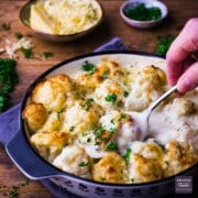 Cauliflower cheese in a black snd white dish with fresh parsley sprinkled over the top