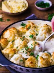 Cauliflower cheese in a black snd white dish with fresh parsley sprinkled over the top