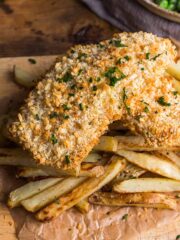 Two fillets of fish in golden bread crumbs sat on a pile of homemade oven chips