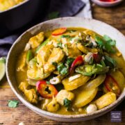 A bowl of massaman curry with sliced new potatoes and chunks of chicken.